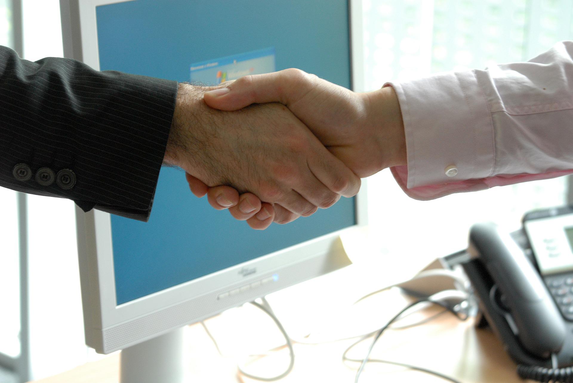 two people shaking hands across a desk